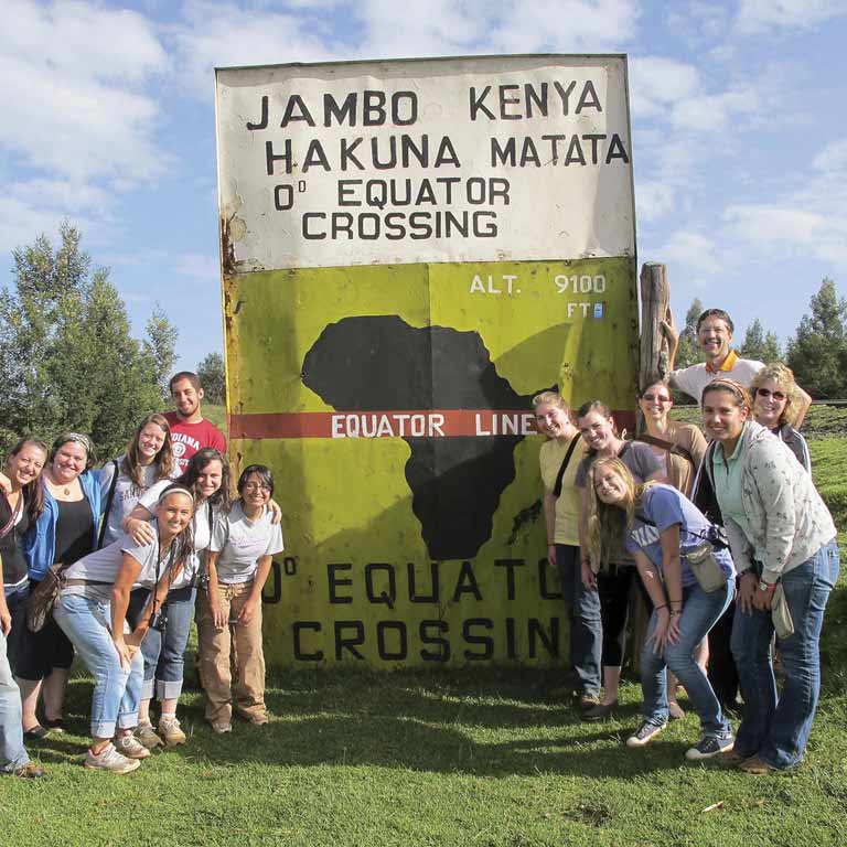 students standing in a front of a sign that has a stencil  of Africa on it